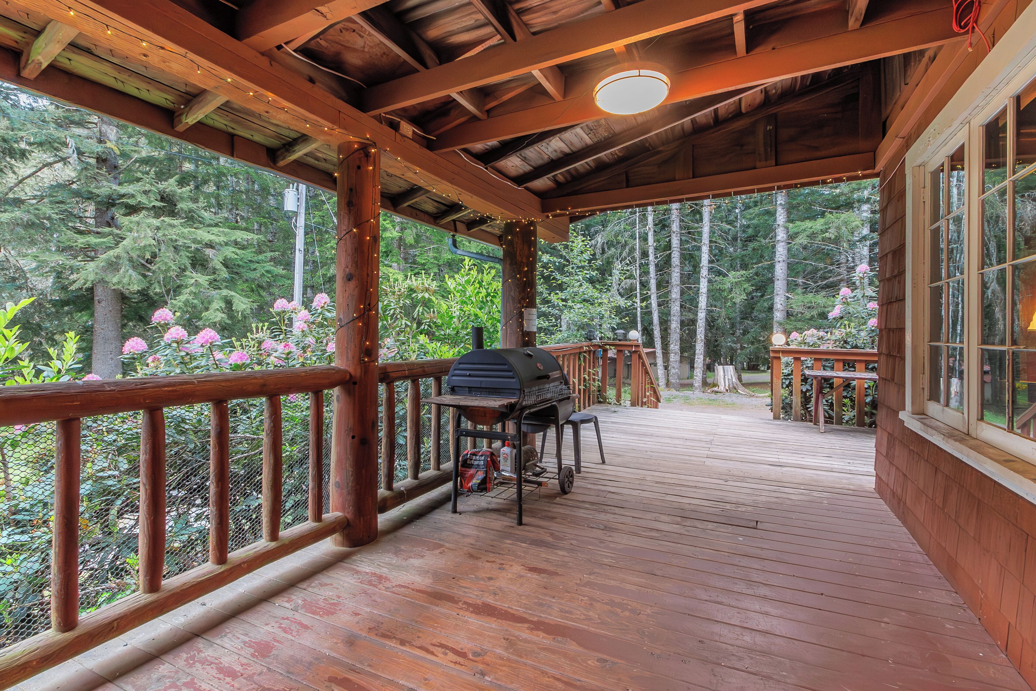 Une terrasse en bois avec un barbecue, une table et un banc.