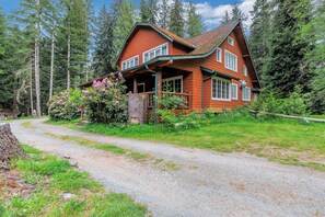 A wooden cabin with a porch, surrounded by trees.