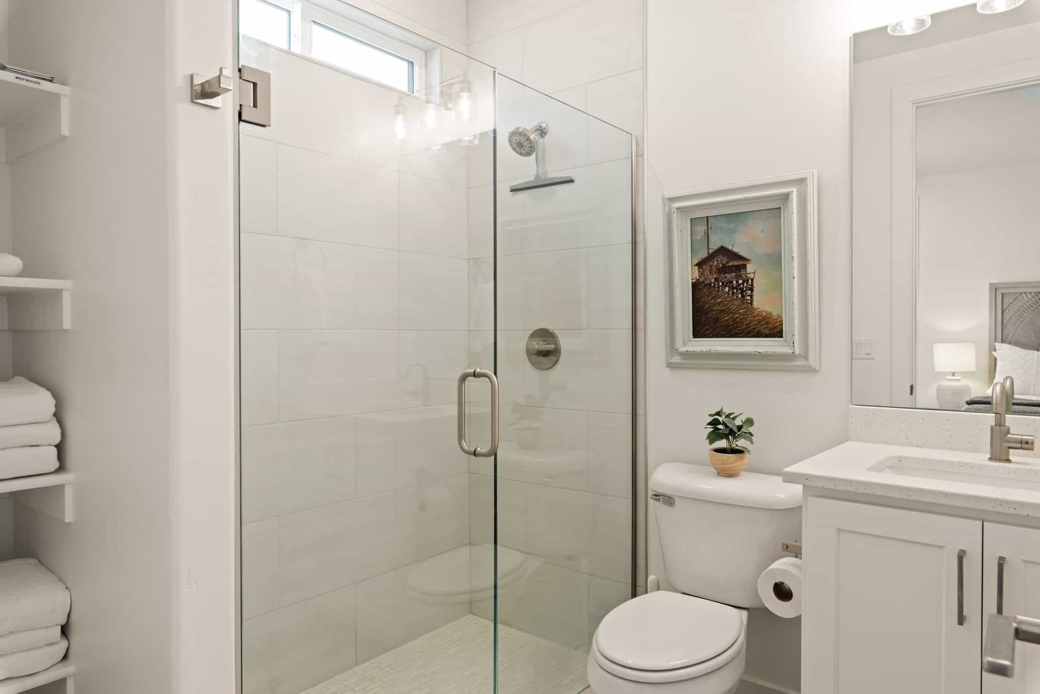 A modern bathroom with a glass-enclosed shower, a toilet, and a sink.