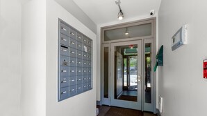 A hallway with a metal filing cabinet, a glass door entrance, and a fire alarm on the wall.