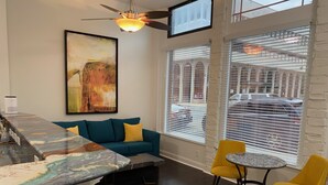 A modern living room with a teal sofa, a marble coffee table, and a yellow chair.