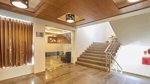 A hotel lobby with a staircase, a reception desk, and a modern interior design.