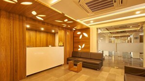 A modern reception area with a wooden reception desk, a sofa, and a glass partition.