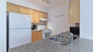 A compact kitchen with a white refrigerator, a stove, a sink, and wooden cabinets. - 2 Bedroom/2 Bathroom Suite (Scarborough)