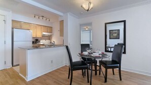 A modern kitchen with a built-in island, dining area with a round table and four chairs, and a large mirror on the wall. - 2 Bedroom/2 Bathroom Suite (Scarborough)