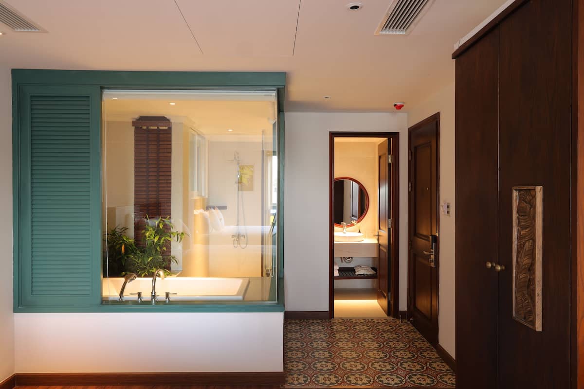 A hallway with a large window, a wooden door, and a patterned floor.
