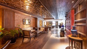 A spacious lobby with wooden flooring, a brick wall, and a high ceiling with exposed beams. There are several seating areas with chairs and tables, and a large vase on a table. - Cochin Sang Hotel (Ho Chi Minh City)