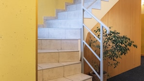 A staircase with a glass railing, beige steps, and a yellow wall with directional signs. - Romantic attic 1/3 room  (Izola)