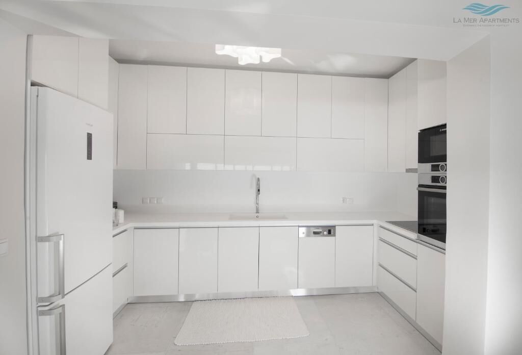 A modern kitchen with white cabinetry, a built-in dishwasher, and a black oven.