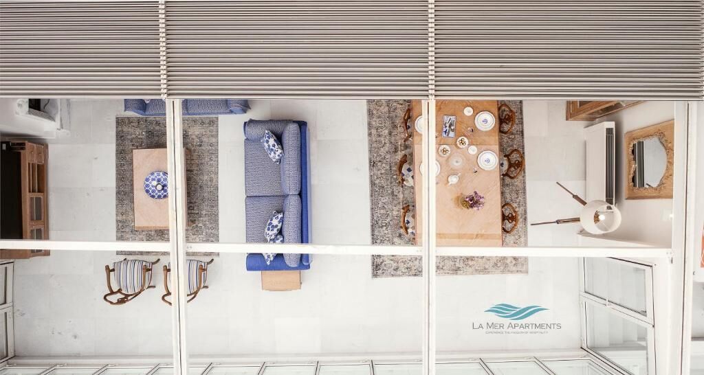 Ein modernes Apartment mit einem blauen Sofa, einem Essbereich mit einem gemusterten Teppich und einer Küche mit weißer Arbeitsplatte.