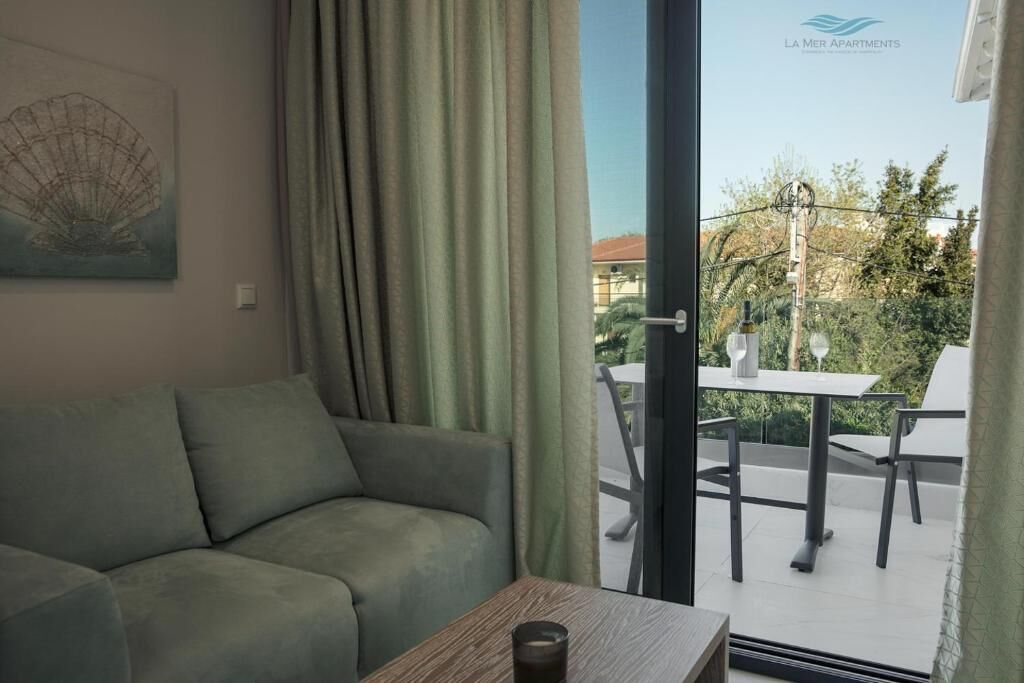 Una sala de estar con un sofá, una mesa y vistas a un patio exterior con mesa y sillas.