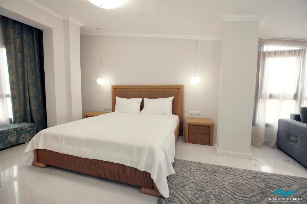 Un dormitorio moderno con una cama grande, mesitas de noche y vistas a la ciudad.