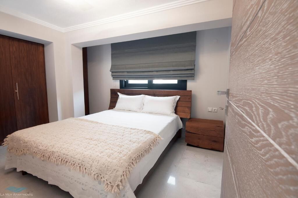 Un dormitorio con cama, mesita de noche, armario de madera y ventana con persiana.