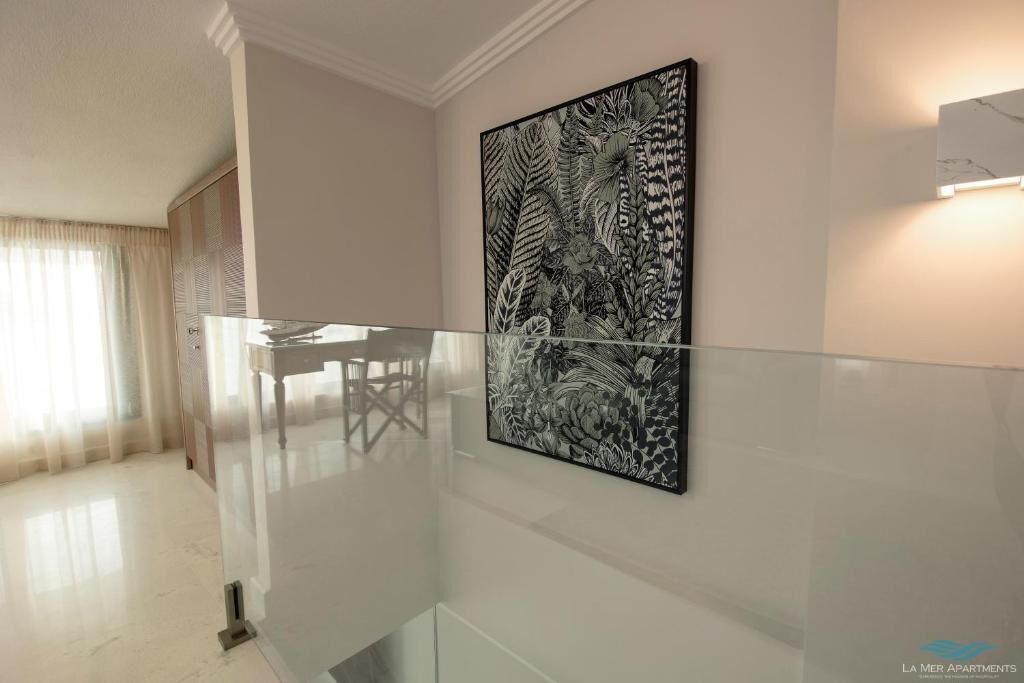 A modern interior with a glass railing, a dining table, and a large black and white floral artwork on the wall.