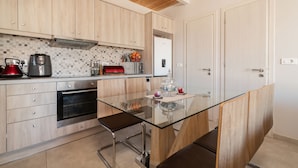 A modern kitchen with wooden cabinets, a glass-top island, stainless steel appliances, and a tiled backsplash. - Sweet Cottage Retreat (Zakynthos)