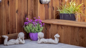 A wooden deck with a purple flower pot, two white statues, and a black planter with green plants. - Sweet Cottage Retreat (Zakynthos)