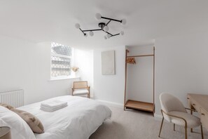 A minimalist bedroom with a bed, a chair, a desk, and a hanging light fixture. - 💫 Chic 2-Bed Apartment in Historic Guest House | Central Rothbury Retreat (Rothbury)
