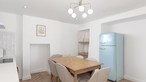 Eine moderne Küche mit Holztisch, Stühlen, einem hellblauen Kühlschrank und einer Pendelleuchte.