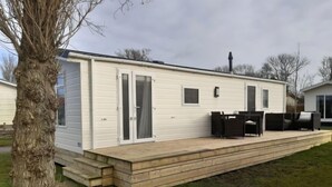 A mobile home with a deck and outdoor furniture.