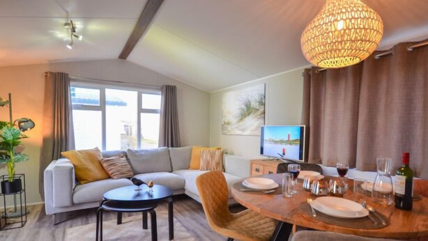 A modern living room with a sofa, coffee table, and dining table set for a meal.