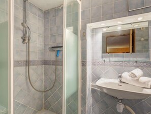 Un baño con ducha de vidrio, un lavabo con espejo y un perchero para toallas.