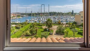 Ein Yachthafen mit zahlreichen Booten, blauem Himmel und gepflegter Bepflanzung.