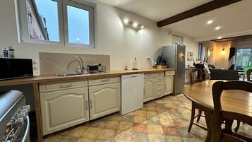 A kitchen with a dishwasher, stove, and a dining area with a table and chairs.