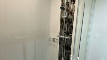 Een moderne douche met een muur met luipaardprint, een glazen deur en een metalen douchekop.