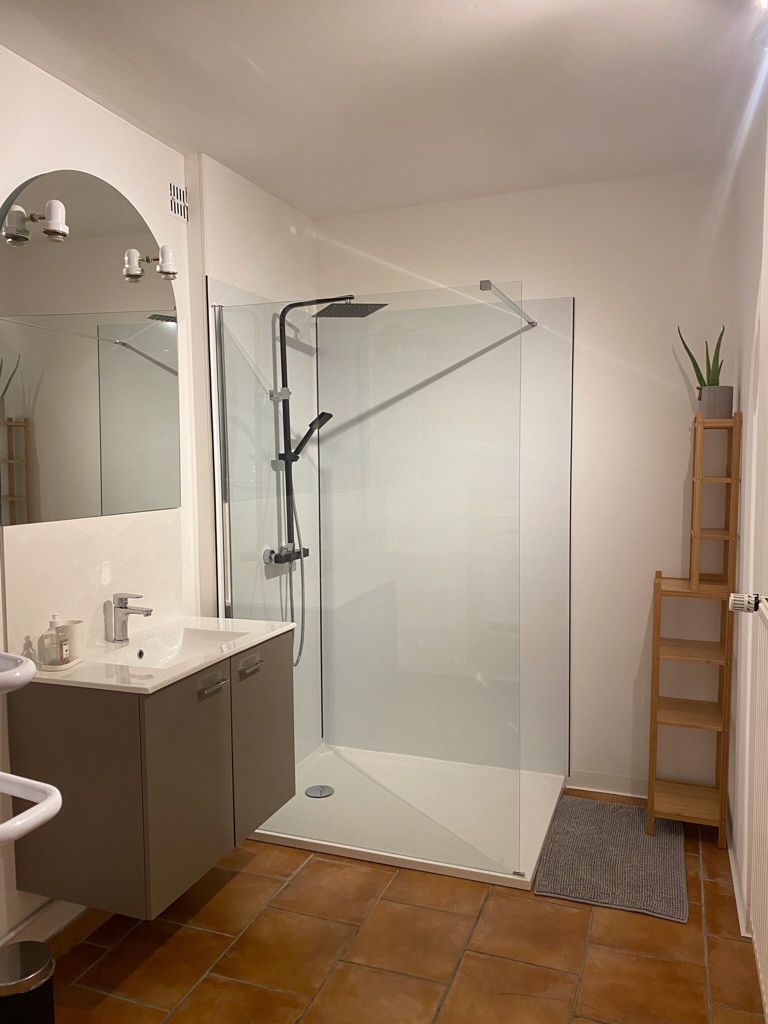 Een moderne badkamer met een douchecabine van glas, een wastafelmeubel en een spiegel.