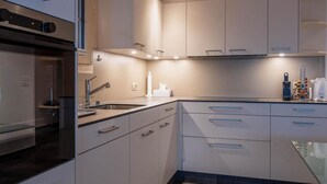 A modern kitchen with white cabinets, a stainless steel sink, and a built-in oven. - Untere Bühlstrasse 10 - EG by Interhome (Lenk)