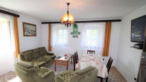 A living room with a sofa set, a dining table with chairs, a chandelier, and a television on the wall. - Vlhlavy u Hluboké by Interhome (Hluboka nad Vltavou)