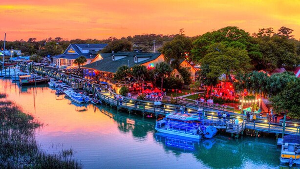 A marina with boats docked, a waterfront restaurant, and a bridge connecting the dock to the shore. - Modern Tropical Bungalow, 3BR 2 Bath (Murrells Inlet)