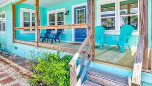 A turquoise house with a porch, blue chairs, and a wooden deck. - Modern Tropical Bungalow, 3BR 2 Bath (Murrells Inlet)