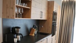 Eine moderne Küche mit Holzschränken, einer schwarzen Arbeitsplatte und einem eingebauten Backofen.