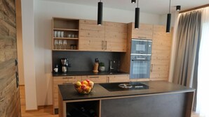 Eine moderne Küche mit Holzausstattung, einer zentralen Kochinsel, Weinkühlschrank und Pendelleuchten.