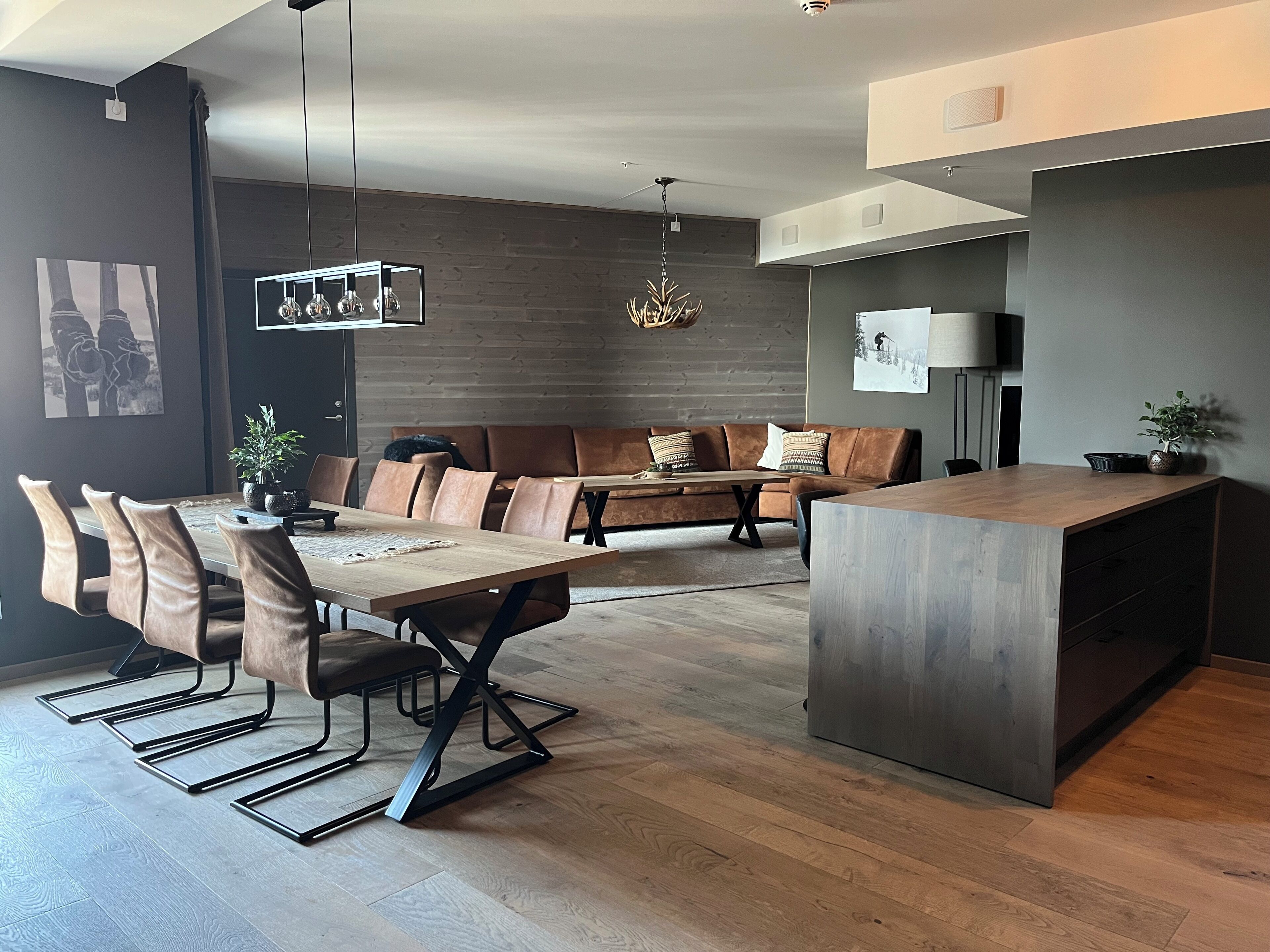 A modern kitchen with a wooden dining table, leather seating, and pendant lighting.