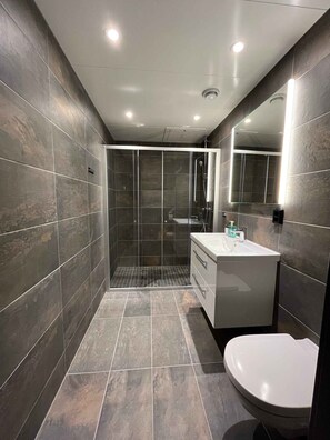 A modern bathroom with a glass-enclosed shower, a white vanity, and a large mirror.