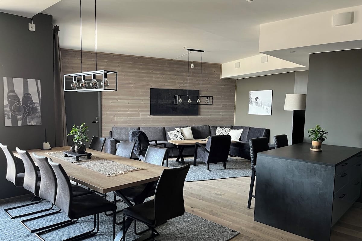 A modern living room with a dining area, featuring a sofa, chairs, a coffee table, and a kitchen island.