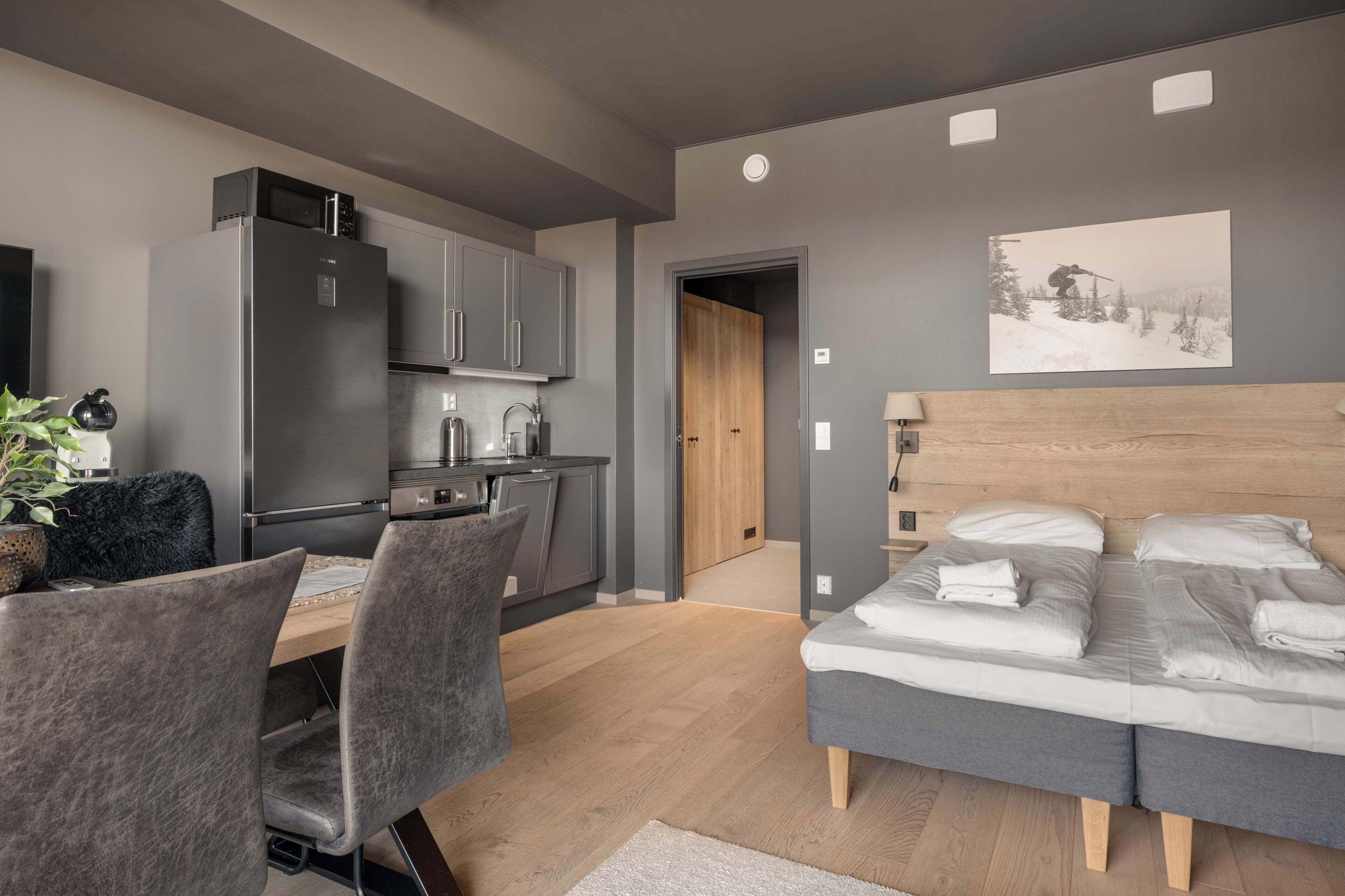Une chambre à coucher moderne, avec un lit, des tables de chevet et une vue sur la cuisine.