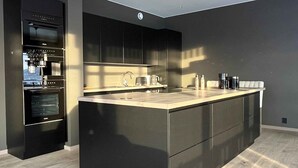 Una cocina moderna con una isla central, electrodomésticos integrados y piso de madera clara.