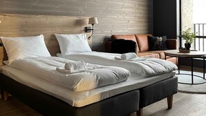 Un dormitorio moderno con una cama grande, un sofá, una mesita y vistas al exterior.