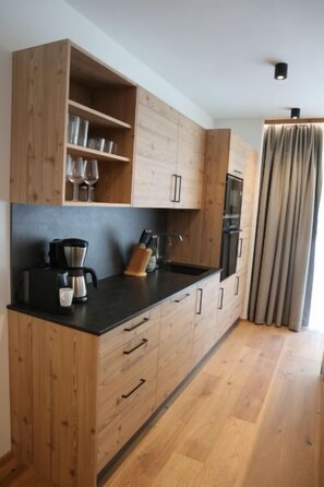 A modern kitchen with wooden cabinets, a black countertop, and stainless steel appliances.