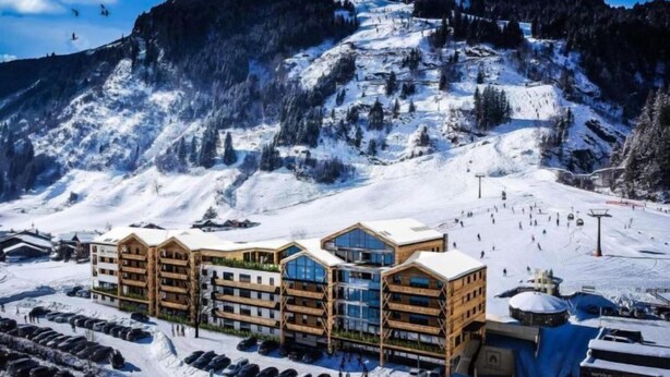 Una stazione sciistica con un edificio a più piani caratterizzato da ampie finestre e una seggiovia sullo sfondo.