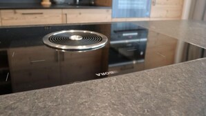 Una cucina moderna con un piano cottura a induzione, un forno integrato e un frigorifero in acciaio inossidabile.