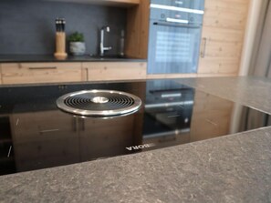 Une cuisine moderne dotée d’une plaque de cuisson à induction noire et d’une hotte en acier inoxydable.