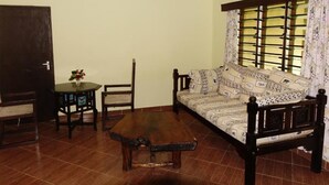 Ein Wohnzimmer mit einer Couch, einem Holztisch, einem kleinen Tisch mit einer Vase und einem Sessel.