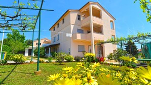 A multi-story residential building with balconies, surrounded by a well-maintained garden with yellow flowers. - Apartment 1779/53709 (Istria - Banjole), 550m from the beach (Banjole)