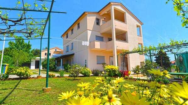 A multi-story residential building with balconies, surrounded by a well-maintained garden with yellow flowers. - Apartment 1779/53710 (Istria - Banjole), 550m from the beach (Banjole)