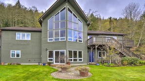 A two-story house with a large bay window, a deck with stairs, and a well-maintained lawn. - Idyllic Retreat ~ 20 Mi to Olympic National Park! (Port Angeles)