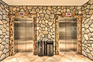 Elevators with digital displays are conveniently located in this area, accompanied by trash and recycling facilities.